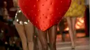 Seorang model membawakan busana berbentuk buah Strawberry karya Charlotte Olympia dalam Fashion Week Spring/Summer 2017 di London, Inggris, (18/9). (REUTERS/Neil Hall)