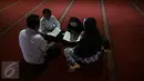 Sebuah keluarga membaca kitab suci Alquran pada bulan Ramadan 1437 H di Masjid Istiqlal, Jakarta, Jumat (7/1). Bulan Ramadan merupakan momentum bagi umat Islam untuk memperbanyak ibadah. (Liputan6.com/Faizal Fanani)