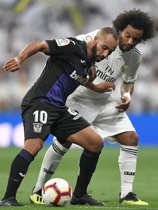Bek Real Madrid, Marcelo, berebut bola dengan pemain depan Leganes, Nabil El Zhar pada laga leg pertama babak 16 besar Copa del Rey di Santiago Bernabeu, Rabu (9/1). Real Madrid sukses mengandaskan Leganes dengan skor 3-0. (GABRIEL BOUYS / AFP)