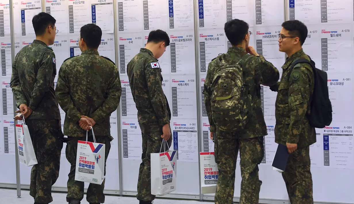 Tentara Korea Selatan membaca informasi pekerjaan saat mengikuti job fair di ruang pameran KINTEX, Goyang, Korea Selatan, Rabu (20/3). Job fair ini diharapkan dapat menarik sekitar 20.000 tentara yang akan segera diberhentikan. (JUNG Yeon-Je/AFP)