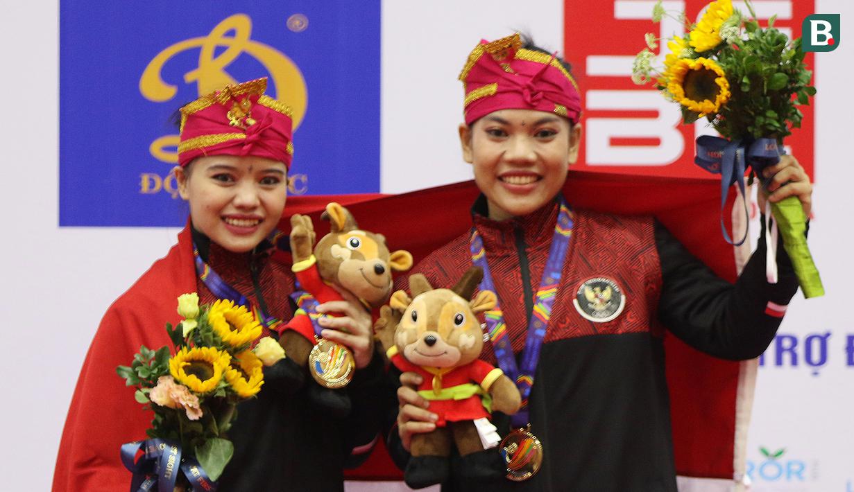 Pesilat Indonesia Riska Hermawan (kiri) dan Ririn Rinasih menunjukkan medali emas dalam nomor Seni Ganda Wanita Pencak Silat Sea Games 2021 Vietnam di Bac tu Liem Sport Center, Hanoi, Rabu (11/5/2022). (Bola.com/Ikhwan Yanuar)