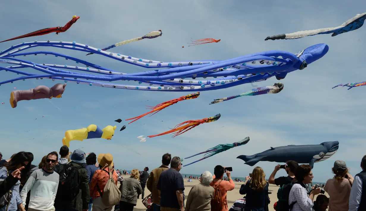 Penonton menyaksikan layang-layang raksasa yang terbang selama Festival Internacional del Viento di pantai Malvarrosa, di Valencia, Spanyol (23/4). Acara ini diikuti oleh 150 peserta dari berbagai penjuru Eropa. (AFP/Jose Jordan)