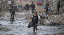 Seorang anak perempuan membawa dua ember kosong saat berjalan menuju tempat mengambil air di tengah hujan deras di kawasan Sheikh Radwan, Kota Gaza, Jumat 14 November 2025. Anak-anak di Gaza masih mengalami kekurangan air bersih. (AP Photo/Jehad Alshrafi)