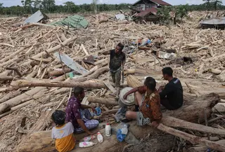 Dalam catatan Badan Nasional Penanggulangan Bencana (BNPB), bencana banjir dan longsor di Aceh Tamiang mengakibatkan kerusakan sebanyak 2.800 unit rumah, 127 fasilitas umum, 62 gedung atau kantor, 54 fasilitas pendidikan, 40 fasilitas kesehatan, 33 rumah ibadah, dan dua jembatan. Tampak dalam foto, warga beristirahat sambil mencari sisa-sisa rumah mereka yang terkubur di bawah tumpukan pohon tumbang yang disapu banjir bandang, di desa Lintang Baru di Aceh Tamiang, Sumatera Utara, pada Kamis 11 Desember 2025. (Aditya Aji/AFP)
