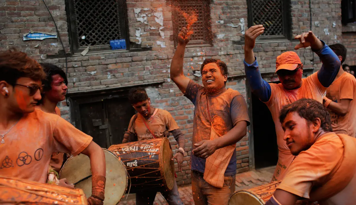 Warga menabuh drum dan menaburkan bubuk vermillion saat perayaan sindoor Jatra festival di Bhaktapur, Nepal (15/4). (AP Photo/Niranjan Shrestha)