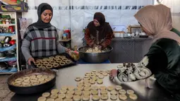 Kaak merujuk pada jenis roti populer yang biasa di kosumsi di seluruh Timur Tengah (Palestina, Lebanon, Suriah, Yordania). Tampak dalam foto, para wanita menyiapkan biskuit tradisional "kaak" yang berbentuk cincin menjelang Idul Fitri, hari raya yang menandai berakhirnya bulan puasa suci Ramadan, di Kota Gaza pada 16 Maret 2026. (Omar AL-QATTAA/AFP)