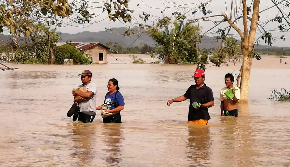 Warga mengarungi jalan raya yang banjir terjangan topan Phanfone di Ormoc City, Provinsi Leyte, Filipina, Rabu (25/12/2019). Topan membuat jutaan warga di negara yang mayoritas beragama Katolik itu merayakan Natal dengan kesedihan. (RONALD FRANK DEJON/AFP)