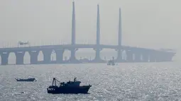 Sebuah perahu berlayar dekat jembatan Hong Kong-Zhuhai-Macau di kota Zhuhai, China selatan, Rabu (28/3). Jembatan laut terpanjang di dunia itu menghubungkan Hong Kong, Macau, dan Zhuhai—tiga kota terpenting dan makmur di China. (AP Photo/Kin Cheung)