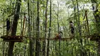 Pengunjung melintasi jalan setapak antarpepohonan di Edenland Park, Balotesti, Rumania, Rabu (4/10/2023). Edenland Park merupakan tempat petualangan terbesar di Rumania. (Liputan6.com/Herman Zakharia)