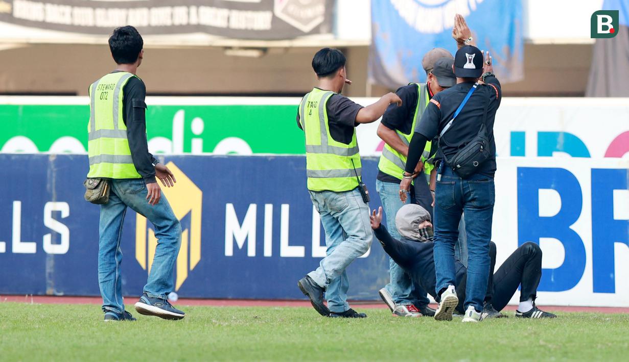 Petugas keamanan menangkap suporter yang masuk ke lapangan saat Persib Bandung melawan Persik Kediri pada laga BRI Liga 1 2022/2023 di Stadion Pakansari, Bogor, Rabu (8/3/2023). (Bola.com/M Iqbal Ichsan)