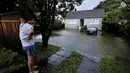 Seorang pria meninjau kerusakan akibat banjir di luar rumahnya di Auckland, Selandia Baru, Rabu (1/2/2023). Peringatan hujan lebat untuk Auckland dicabut, meskipun keadaan darurat tetap berlaku untuk kota terbesar di negara itu setelah curah hujan dan banjir yang mencapai rekor. pada hari Jumat menewaskan empat orang dan menyebabkan gangguan yang meluas. (Brett Phibbs/New Zealand Herald via AP)