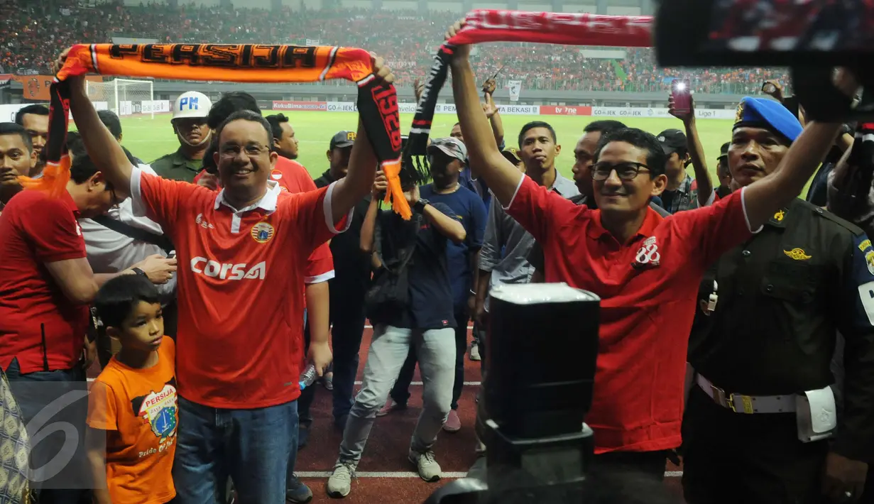 Cagub dan Cawagub DKI Jakarta Anies Baswedan bersama Sandiaga Uno mengangkat syal usai menonton pertandingan Persija VS Barito Putra di Stadion Patriot Bekasi, Sabtu (22/4). ). Anies hadir dengan mengenakan jersey Persija. (Liputan6.com/Gempur M. Surya)