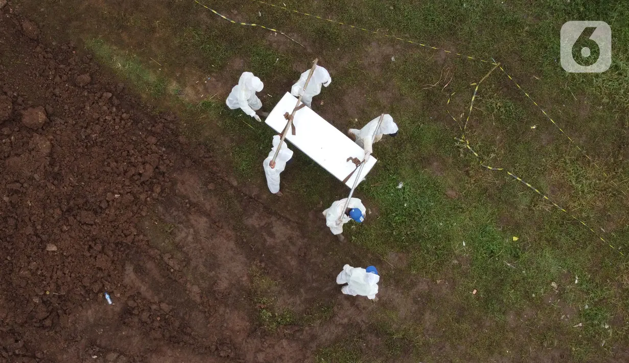 Foto udara petugas membawa peti jenazah dengan protokol COVID-19 di TPU Srengseng Sawah, Jakarta, Kamis (21/1/2021). Sebagian lahan TPU Srengseng Sawah yang dijadikan lokasi pemakaman jenazah Covid-19 sejak Selasa (12/1) lalu, kini hanya tersisa 79 petak makam. (Liputan6.com/Helmi Fithriansyah)