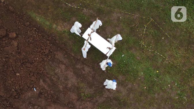 Foto udara petugas membawa peti jenazah dengan protokol COVID-19 di TPU Srengseng Sawah, Jakarta, Kamis (21/1/2021). Sebagian lahan TPU Srengseng Sawah yang dijadikan lokasi pemakaman jenazah Covid-19 sejak Selasa (12/1) lalu, kini hanya tersisa 79 petak makam. (Liputan6.com/Helmi Fithriansyah)