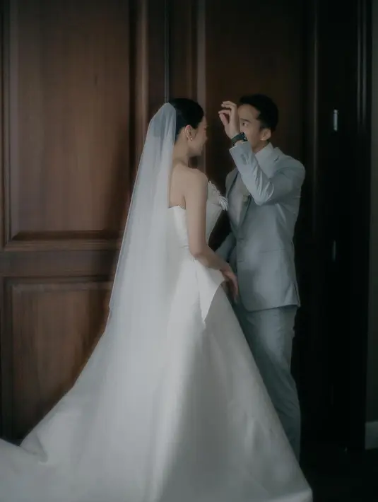 Rambutnya disanggul modern tanpa poni dengan bagian depan rambut belah tengah. Lengkap mengenakan veil panjang. [@elsiechrysila]