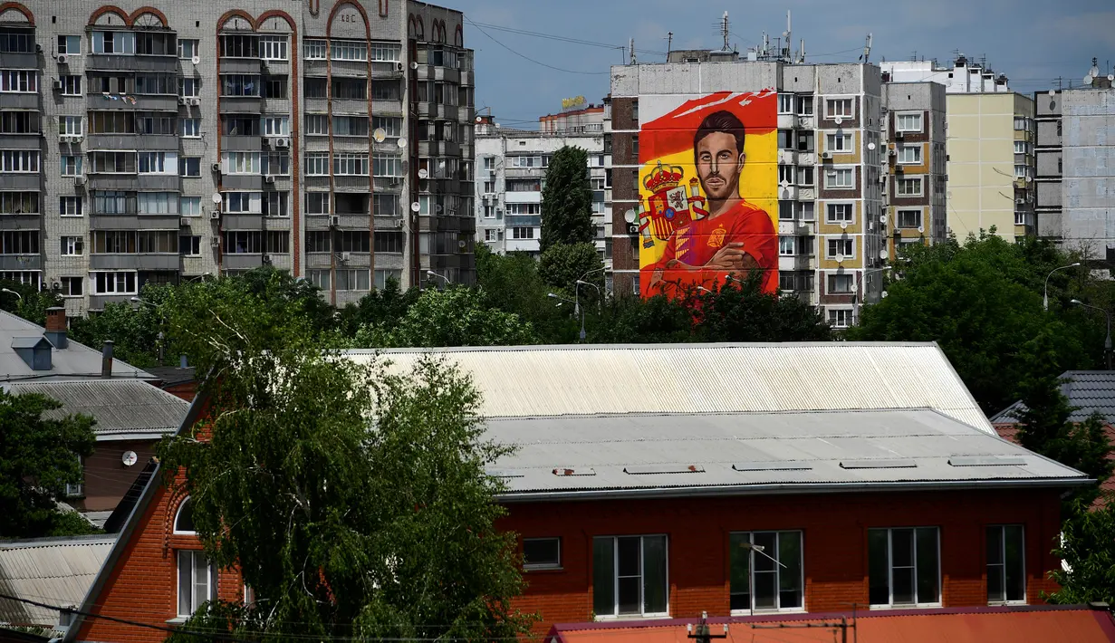 Mural raksasa begambar bek Spanyol Sergio Ramos terlihat di sebuah bangunan perumahan di Krasnodar, Rusia, Rabu (6/6). Mural tersebut muncul jelang kedatangan Ramos dan tim untuk berbasis di Krasnador pada Piala Dunia 2018. (Pierre-Philippe MARCOU/AFP)