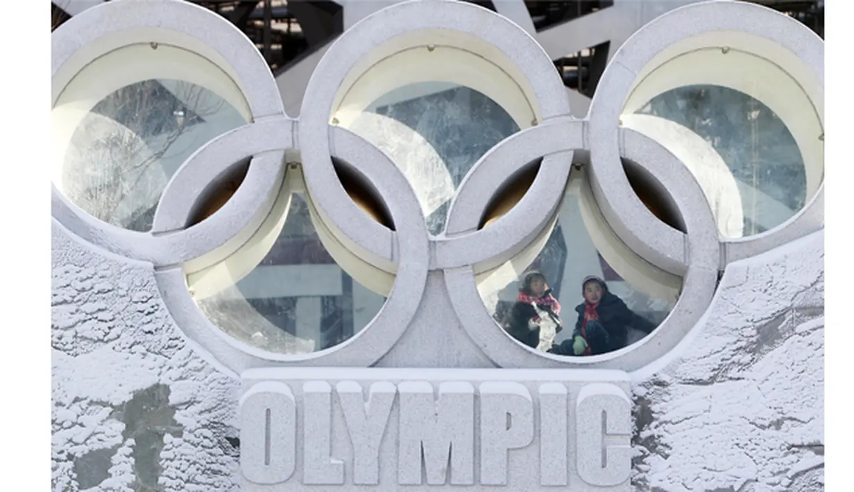 Warga berada di antara logo Olimpiade yang terdapat di luar National Olympic Stadium, Tiongkok, Senin (2/1/2012). Stadium itu rencananya akan digunakan sebagai tempat upacara pembukaan dan penutupan Olimpiade Musim Dingin 2022. (EPA/How Hwee Young).