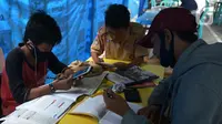 Para siswa belajar online di Tenda Wifi gratis di taman warga RT 013, Jakarta Timur, Rabu (12/8/2020). Tenda belajar tersebut menyediakan fasilitas wifi gratis bagi anak-anak sekolah yang terkendala dengan mahalnya kuota internet. (merdeka.com/Imam Buhori)