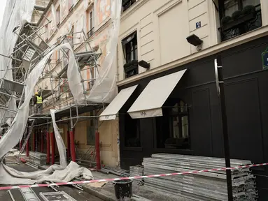 Pekerja melihat kerusakan yang terjadi usai penyangga proyek bangunan ambruk terkena angin kencang di Paris, Prancis (3/1). Tiang penyangga ini berjatuhan akibat terkena angin kencang dari badai Eleanor. (AFP Photo/Stephane De Sakutin)