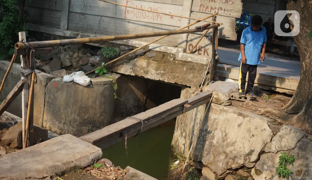Pejalan kaki melewati tembok berlubang di Terminal Kampung Rambutan, Jakarta, Kamis (19/12/2019). Jauhnya akses bagi pejalan kaki menjadikan tembok berlubang tersebut pintu alternatif untuk keluar dan masuk Terminal Kampung Rambutan. (Liputan6.com/Immanuel Antonius)
