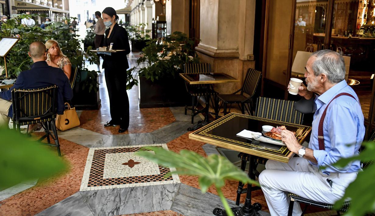 Warga sarapan di sebuah bar di pusat perbelanjaan Vittorio Emanuele II, Milan, Italia, Senin (18/5/2020). Italia secara perlahan melonggarkan kebijakan lockdown akibat pandemi virus corona COVID-19. (Claudio Furlan/LaPresse via AP)