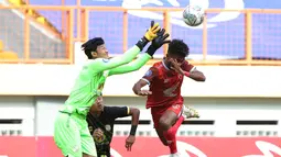 Pemain PSM Makassar, Yakob Sayuri (kanan) berduel udara dengan kiper Barito Putera, Muhammad Riyandi dalam laga pekan ke-5 BRI Liga 1 2021/2022 di Stadion Wibawa Mukti, Cikarang, Senin (27/9/2021). PSM kalah 0-2. (Bola.com/Ikhwan Yanuar)