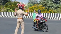 Inspektur polisi Rajesh Babu mengenakan helm berbentuk virus corona saat mengimbau pengendara selama pemberlakukan lockdown di pos pemeriksaan di Chennai, India, Sabtu (28/3/2020). Cara ini agar warga menerapkan social distancing dan tetap berada di rumah selama pandemi Covid-19. (Arun SANKAR/AFP)