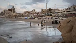 Warga Palestina menata kembali kehidupan mereka di antara puing-puing kehancuran akibat serangan yang dilancarkan Israel sejak Okrober 2023 silam. Tampak dalam foto, seorang peselancar Palestina membawa papan selancarnya ke laut di sepanjang garis pantai di Kota Gaza, Minggu, 28 Desember 2025. (AP Photo/Jehad Alshrafi)
