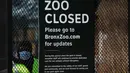 Seorang penjaga berdiri di pintu masuk ke Kebun Binatang Bronx di New York City, Amerika Serikat, Senin (6/4/2020). Saat ini, beberapa harimau di Kebun Binatang Bronx berada dalam perawatan dokter hewan. (Spencer Platt/Getty Images/AFP)