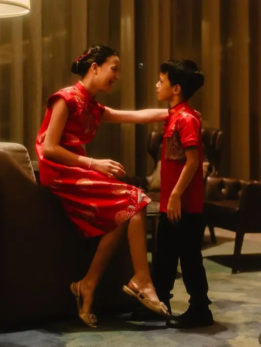 Putri Daniel Manata tampil mengenakan chengosam merah bermotif dipadukan flat shoes. Semantara anak laki-laki mengenakan atasan merah lengan pendek dipadukan celana panjang hitam.   [@ferrysunarto_official]