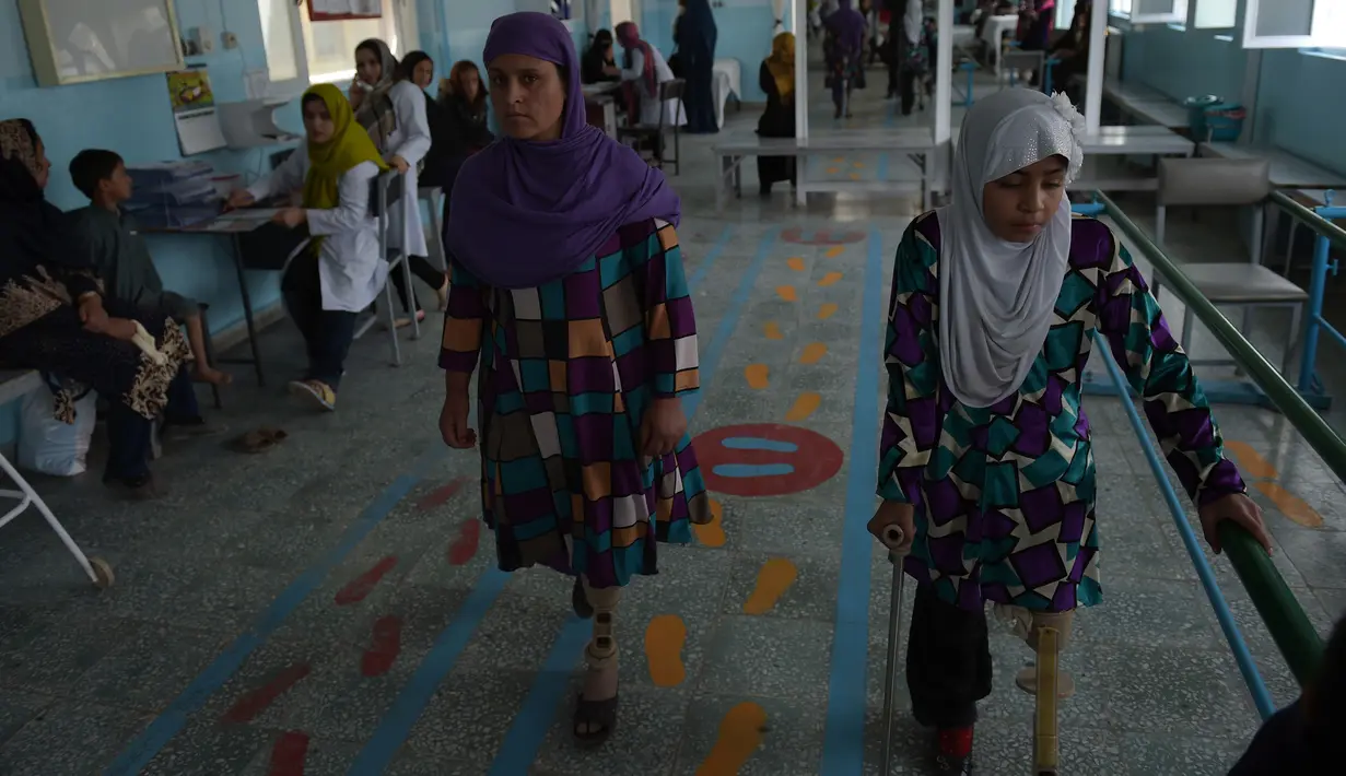 Wanita Afgan berlatih menggunakan kaki palsu, dibantu menggunakan tongkat, di pusat ortopedik Komite Internasional Palang Merah (ICRC), rumah sakit bagi korban perang dan yang diamputasi, di Kabul, Minggu (3/4).  (SHAH Marai/AFP)