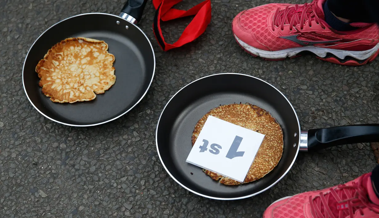 Kaia Larkas usai memenangkan lomba lari sembari membawa wajan berisi pancake di Kota Olney, Buckinghamshire, Inggris, Selasa (28/2). Lomba yang digelar pada Hari Pancake atau Pancake Day ini diadakan satu hari menjelang Rabu Abu. (AP Photo/Alastair Grant)