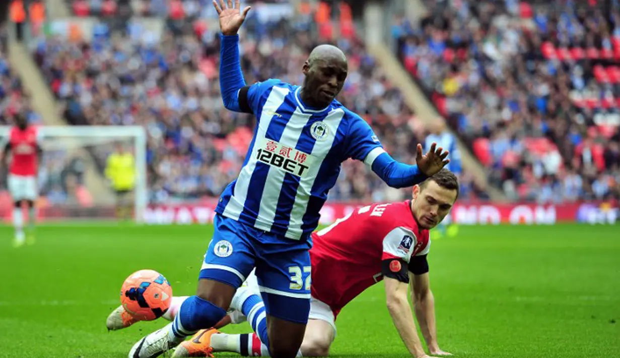 Striker Wigan Athletic, Marc-Antoine Fortune (kiri) mendapat tackling keras dari Thomas Vermaelen dalam laga Semi-final Piala FA di Stadion Wembley, London (12/4/2014). (AFP PHOTO/Glyn KIRK)