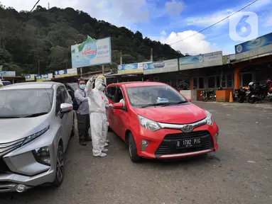 Petugas memeriksa surat keterangan lolos uji rapid test pada warga yang akan melakukan perjalanan di Pos Pam Puncak Pass, Jawa Barat, Minggu (17/5/2020). Ratusan kendaraan dipulangkan ke daerah asalnya dari wilayah Bogor Depok dan Jakarta karena melanggar PSBB parsial.  (merdeka.com/Arie Basuki)