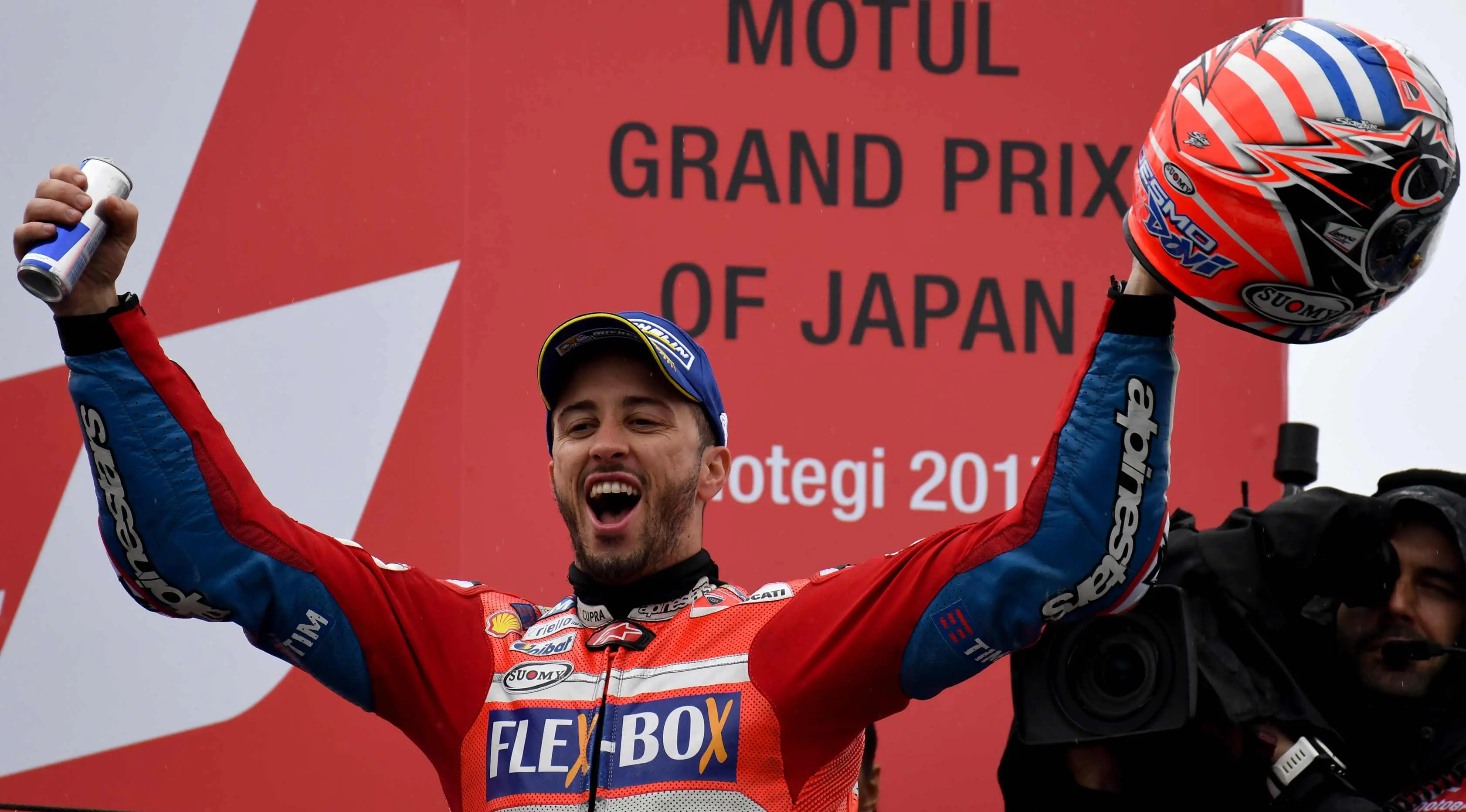 Pembalap Ducati, Andrea Dovizioso merayakan kemenangannya di atas podium usai memenangi MotoGP Jepang di sirkuit Motegi (15/10). Pembalap Ducati ini kini hanya 11 angka tertinggal dari Marc Marquez. (AFP Photo/Toshifumi Kitamura)