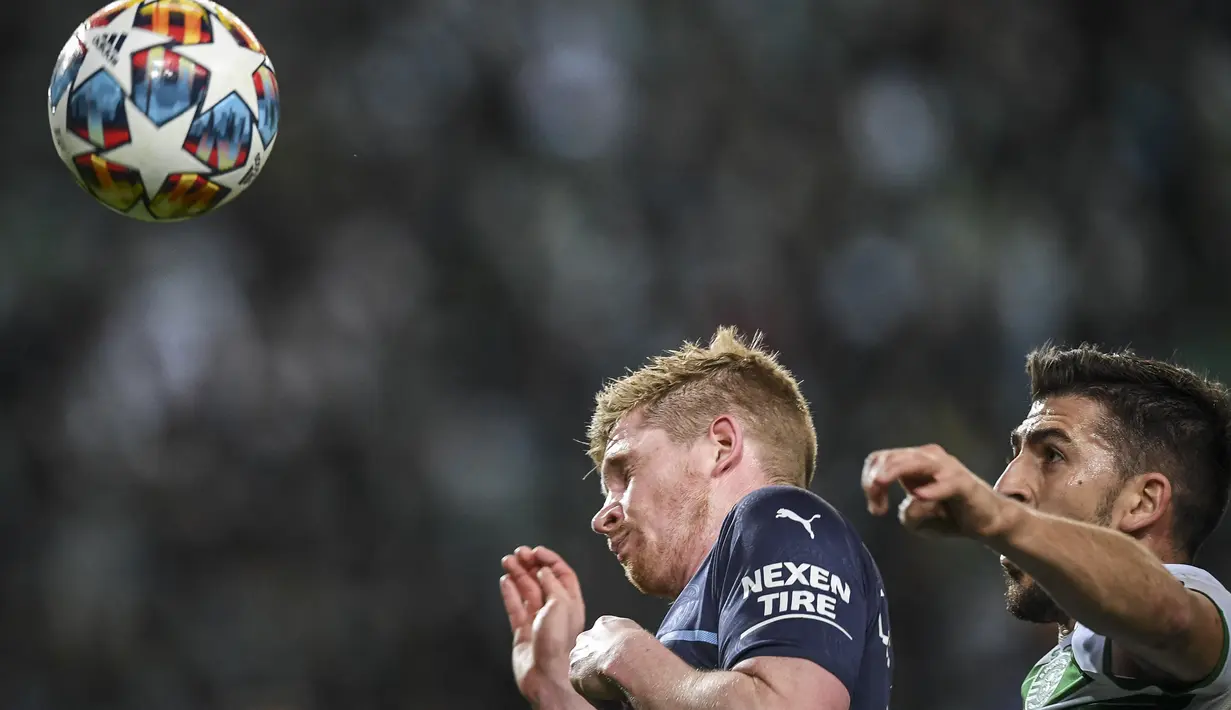 Gelandang Manchester City Kevin De Bruyne dan penyerang Sporting Lisbon Paulinho Dias Fernandes berebut bola pada leg pertama 16 besar Liga Champions di Estadio Jose Alvalade, Rabu (16/2/2022) dini hari WIB.  Manchester City mengalahkan tuan rumah Sporting CP 5-0. (PATRICIA DE MELO MOREIRA/AFP)
