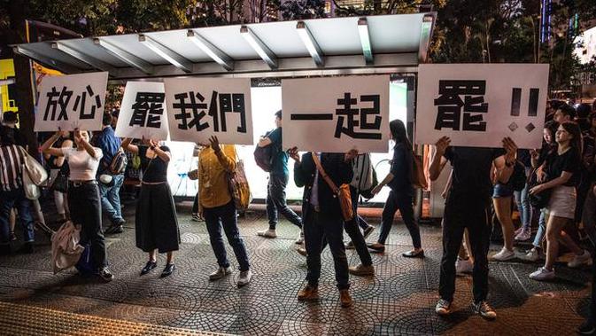 Demonstran menunjukkan pesan tuntutan mereka saat ribuan pegawai negeri sipil (PNS) mengikuti unjuk rasa menolak RUU Ekstradisi di Hong Kong, Jumat (2/8/2019). Banyak PNS yang memakai topeng hitam untuk menyembunyikan identitas mereka. (LAUREL CHOR/AFP)