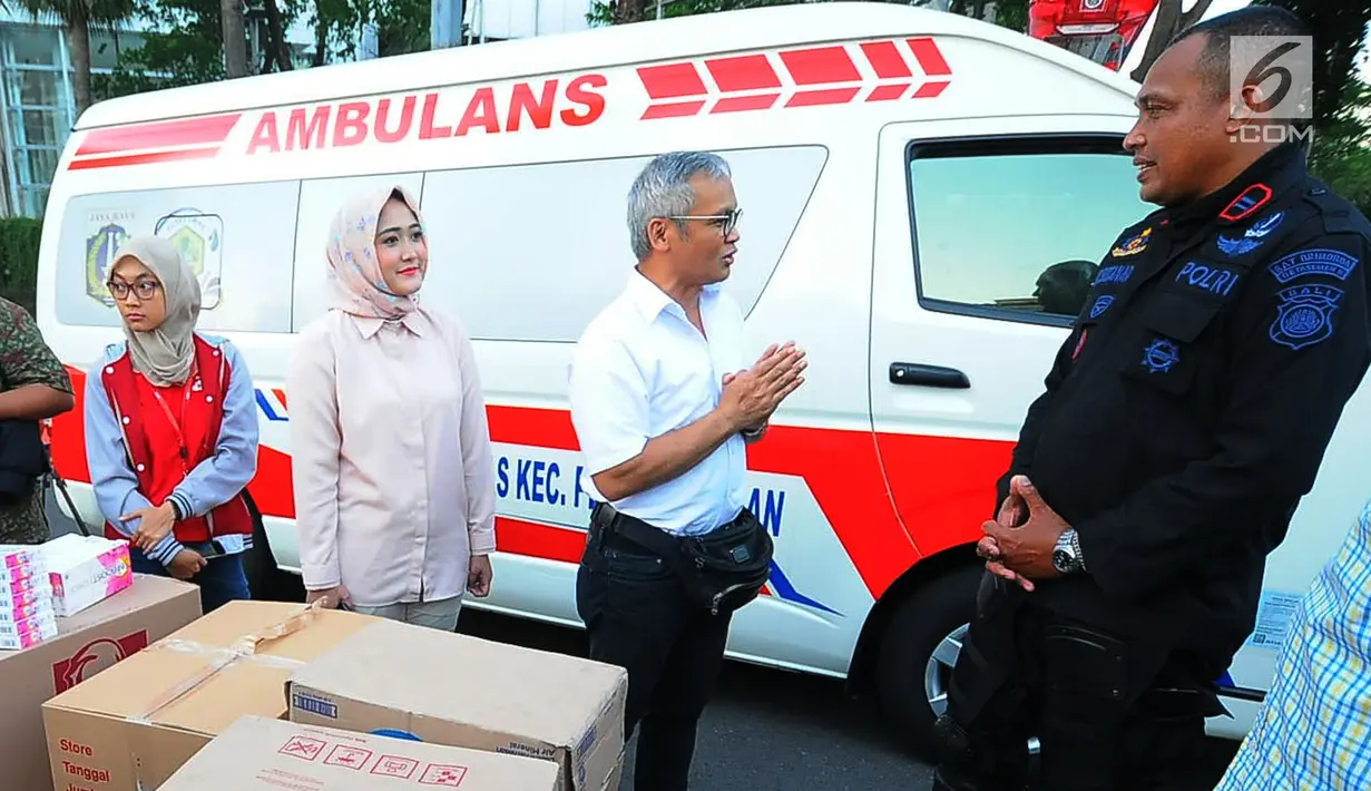 Direktur Program TKN Jokowi-Ma'ruf Amin, Aria Bima (kemeja putih) bersama relawan TKN  membagikan makanan berbuka puasa kepada aparat kepolisian yang melakukan penjagaan di kawasan Bundaran HI, Jakarta, Jumat (24/5/2019). (Liputan6.com/Angga Yuniar)