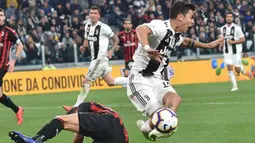 Penyerang Juventus, Paulo Dybala, terjatuh saat berebut dengan pemain AC Milan pada laga Serie A di Stadion Allianz, Turin, Sabtu (6/4). Juventus menang 2-1 atas AC Milan. (AP/Andrea Di Marco)