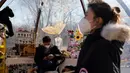 Pedagang yang mengenakan masker menunggu pelanggan di toko popup, Beijing, China, 27 Desember 2022. Perusahaan menyambut baik keputusan China untuk mengakhiri karantina bagi pelancong dari luar negeri sebagai langkah penting untuk menghidupkan kembali aktivitas bisnis yang merosot, sementara Jepang mengumumkan pembatasan pengunjung saat infeksi melonjak. (AP Photo/Ng Han Guan)