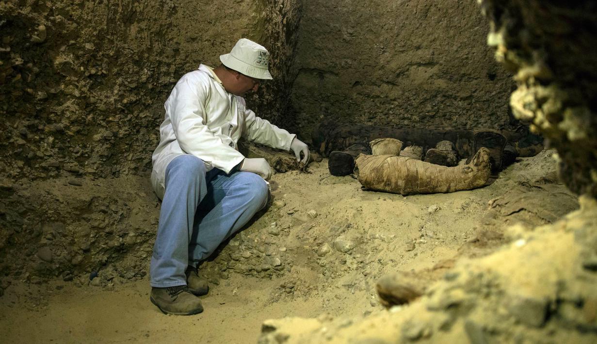 Arkeolog memeriksa mumi terbungkus kain linen di ruang pemakaman di Provinsi Minya, Mesir, Sabtu (2/2). Mumi tersebut diperkirakan berasal dari era Ptolemaic. (AP Photo/Roger Anis)