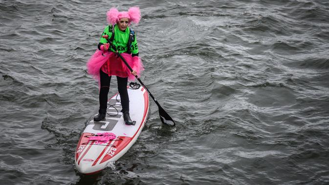 Seorang peserta mengenakan saat lomba dayung sambil berdiri pada edisi ke-10 Nautic Paddle Race di Sungai Seine, Paris, Minggu (8/12/2019). Sekitar 1000 pesaing ikut serta dalam lomba sejauh 11 kilometer menyeberangi sungai Seine dengan pemandangan kota Paris. (Photo by Olivier MORIN / AFP)