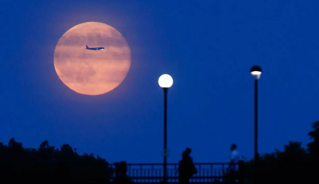 Pesawat tampak membelah sinar bulan purnama di Ottawa, Kanada   (REUTERS/Blair Gable)