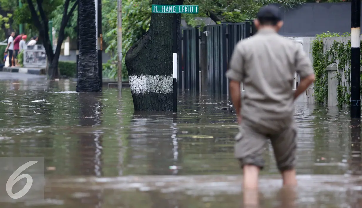 Warga berjalan melintasi banjir yang menggenangi Kommplek Perumahan yang Banjir di Hang Lekiu, Kebayoran Baru, Jakarta, Jumat (11/11). Hujan deras disertai angin yang mengguyur wilayah Jakarta, mengakibatkan daerah ini banjir. (Liputan6.com/Johan Tallo)