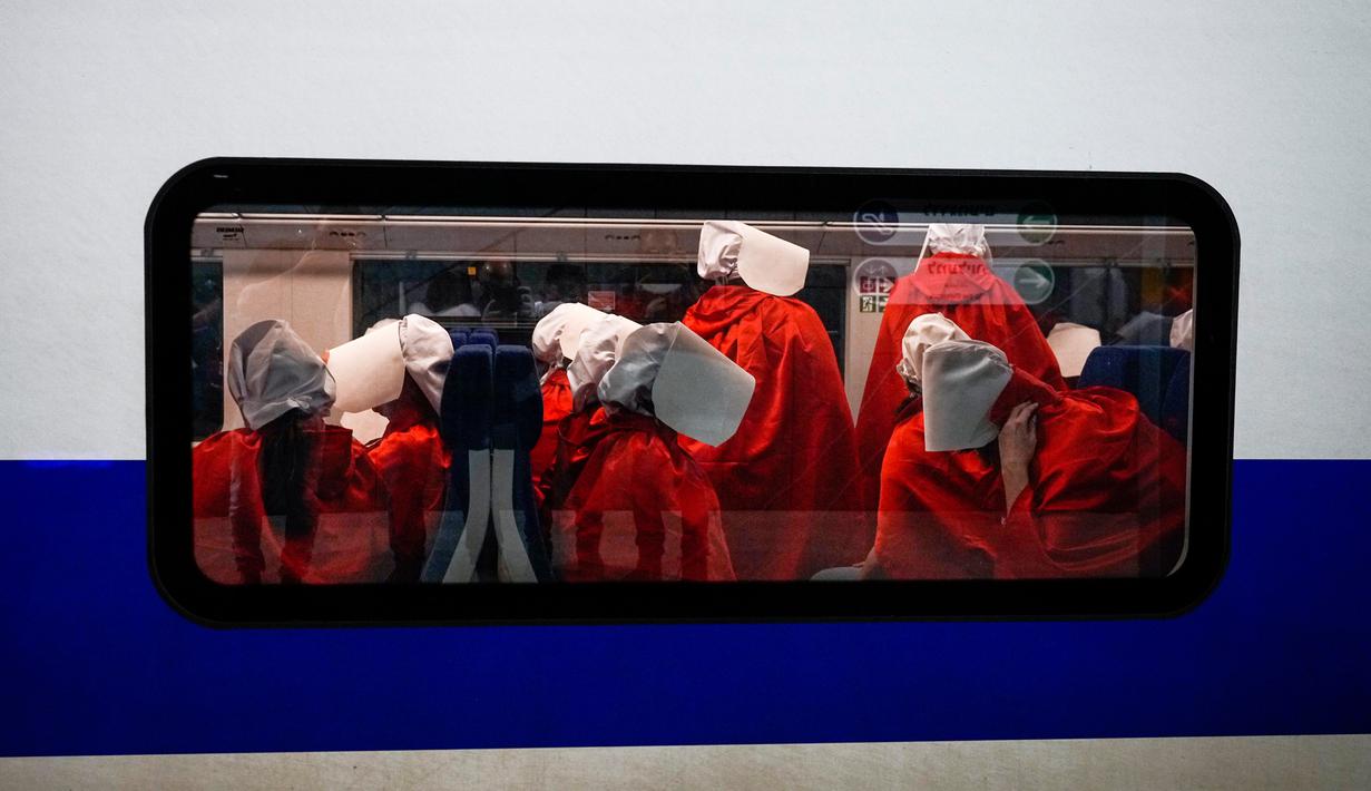Pengunjuk rasa yang mendukung hak-hak perempuan berpakaian seperti karakter dari serial TV "The Handmaid's Tale" saat melakukan perjalanan untuk memprotes rencana pemerintah baru Perdana Menteri Benjamin Netanyahu untuk merombak sistem peradilan di sebuah stasiun kereta api di Yerusalem, Israel, 1 Maret 2023. Mengacu pada fenomena yang berkembang, harian Inggris The Guardian menggambarkan penampilan para pelayan sebagai salah satu simbol paling kuat dari protes feminis kontemporer. (AP Photo/Ohad Zwigenberg)