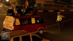 Petugas kepolisian memberhentikan sebuah mini bus di kawasan Matraman, Jakarta Timur, Jum’at (17/7/15) malam. Mini Bus tersebut melanggar peraturan karena menaikan penumpang diatap saat perayaan malam takbiran.(Liputan6.com/Faisal R Syam)