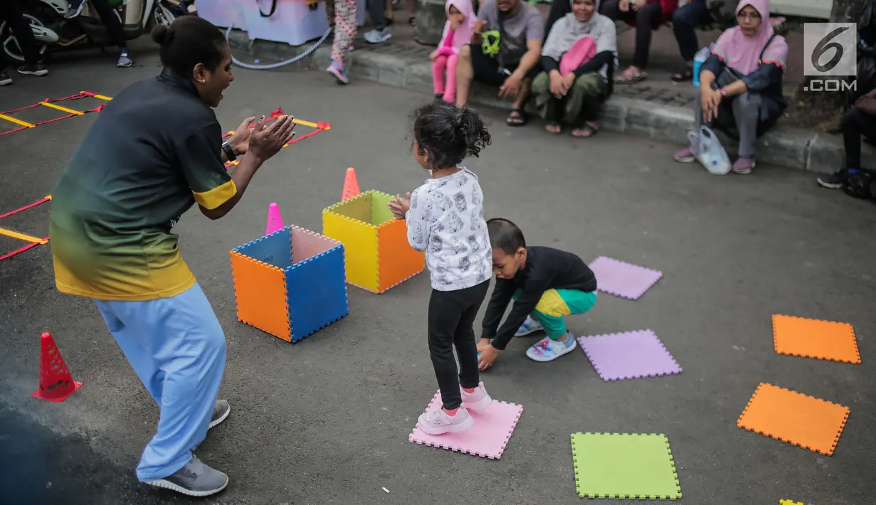 Anak-anak bermain permainan tradisional ditemani sejumlah mahasiswa dari Penggerak Olahraga saat car free day (CFD) di kawasan Bundaran HI, Jakarta, Minggu (14/7/2019). Kegiatan yang rutin digelar ini bertujuan mengajak masyarakat DKI Jakarta aktif berolahraga. (Liputan6.com/Faizal Fanani)