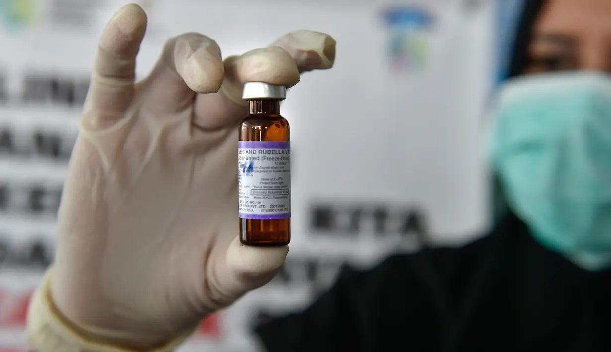Petugas menunjukan Vaksin Campak dan Rubella (MR) sebelum melakukan imuniasasi kepada anak di sebuah puskesmas, Banda Aceh, Rabu (19/9). Pemerintah Aceh memperbolehkan penggunaan vaksin MR dengan alasan dalam kondisi darurat. (CHAIDEER MAHYUDDIN / AFP)