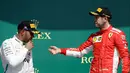 Pembalap Ferrari, Sebastian Vettel (kanan) mengulurkan tangannya ke arah pembalap Mercedes, Lewis Hamilton usai memenangkan F1 GP di Sirkuit Silverstone, Inggris, Minggu (8/7). Vettel berhasil mengungguli Lewis Hamilton. (AP Photo/Luca Bruno)