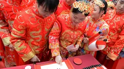 Mempelai membubuhkan sidik jari pada tulisan kaligrafi tradisional dalam pernikahan massal bergaya China di Changsha, Provinsi Hunan, China, 25 September 2020. Sebanyak 71 pasangan resmi menjadi suami-istri usai mengikuti upacara pernikahan tradisional dalam acara nikah massal. (Xinhua/Chen Zhenhai)